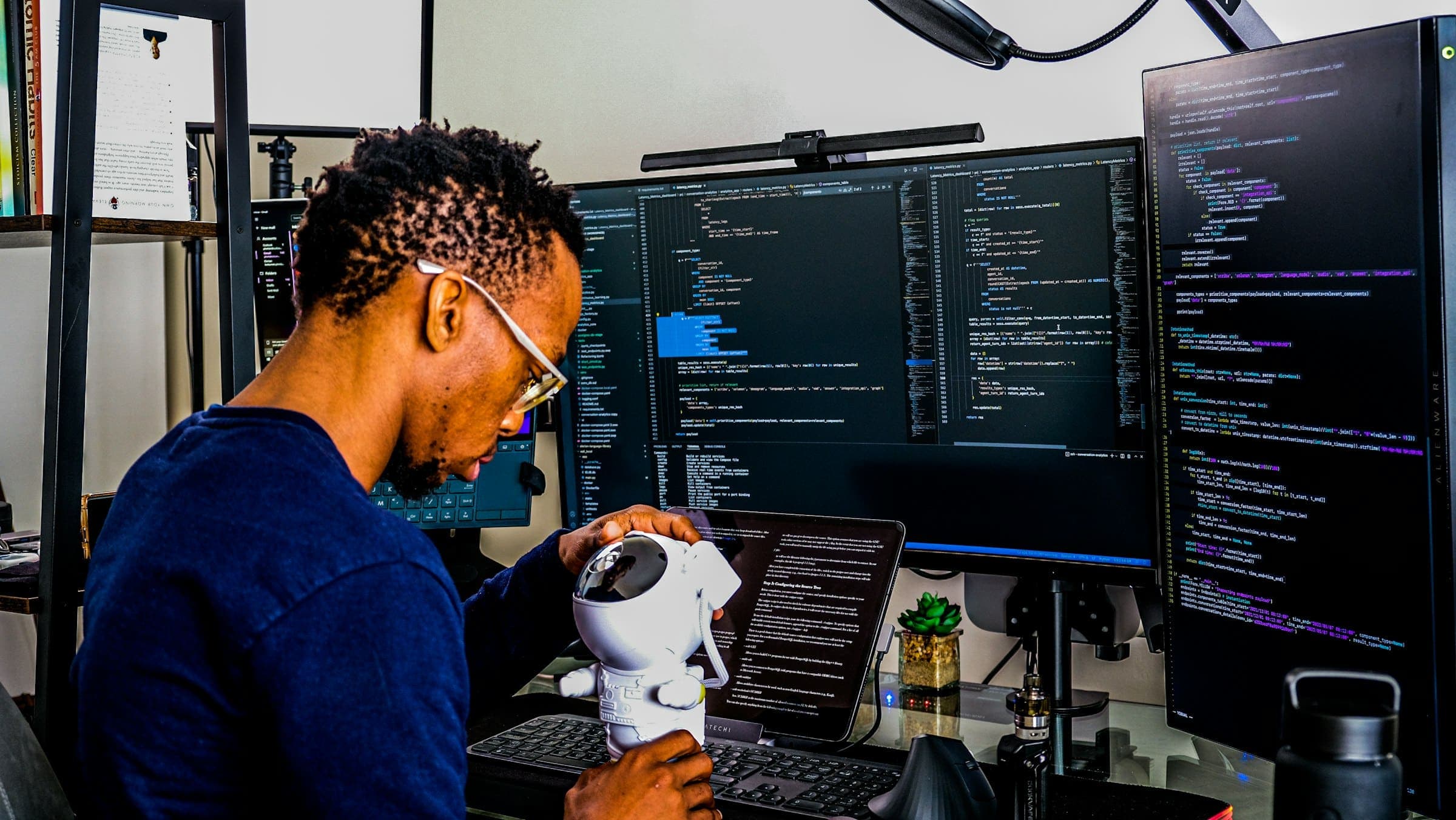 Software developer works at a desk surrounded by multiple monitors displaying code