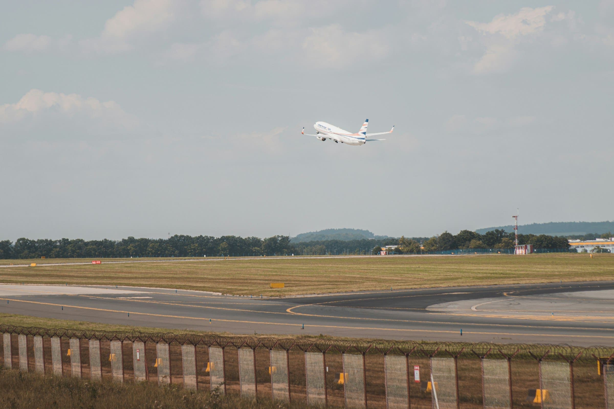 Passenger jet climbing away from an airport runway under a pale sky