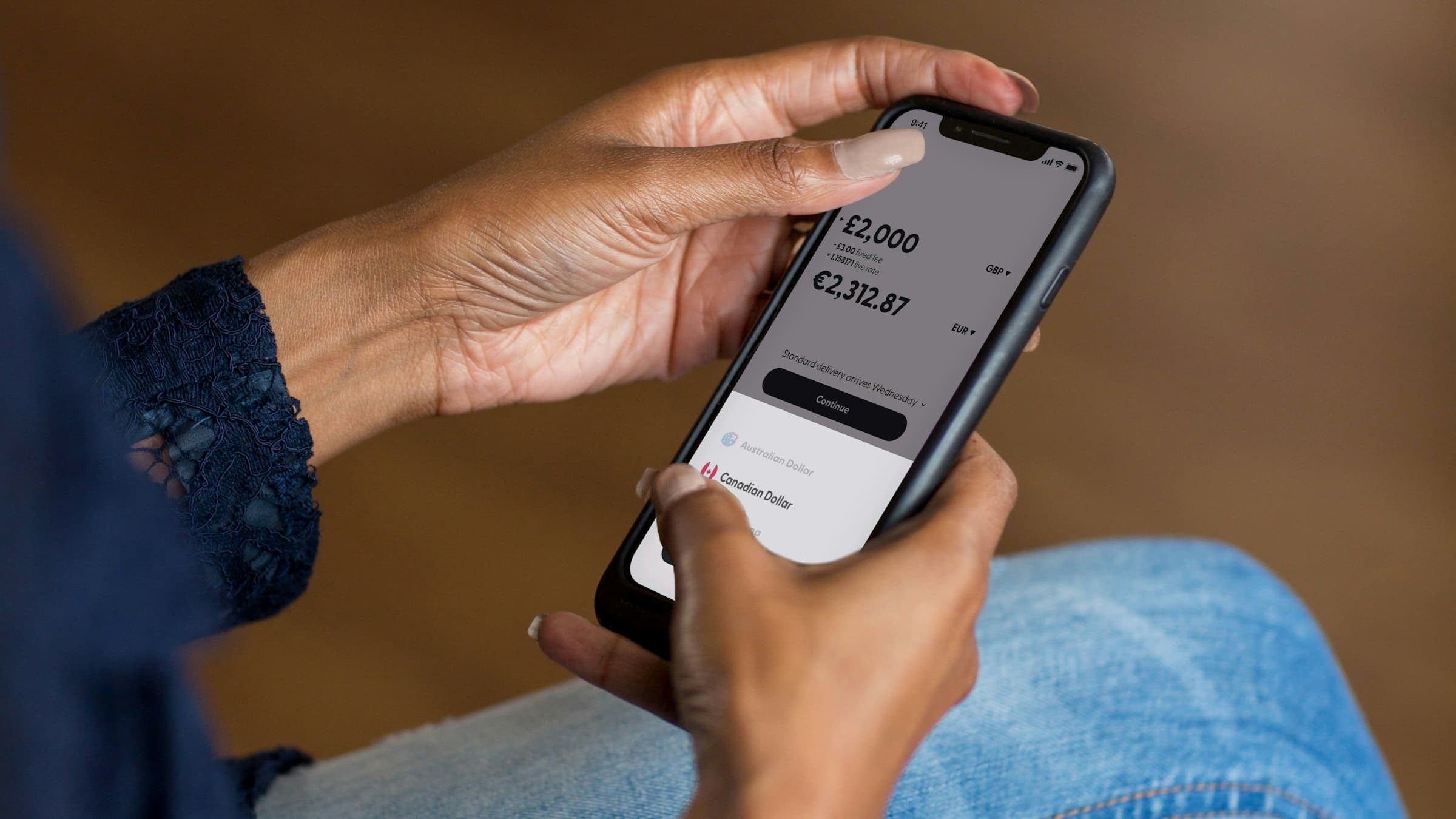 Hands hold a smartphone displaying a money transfer screen with account balance