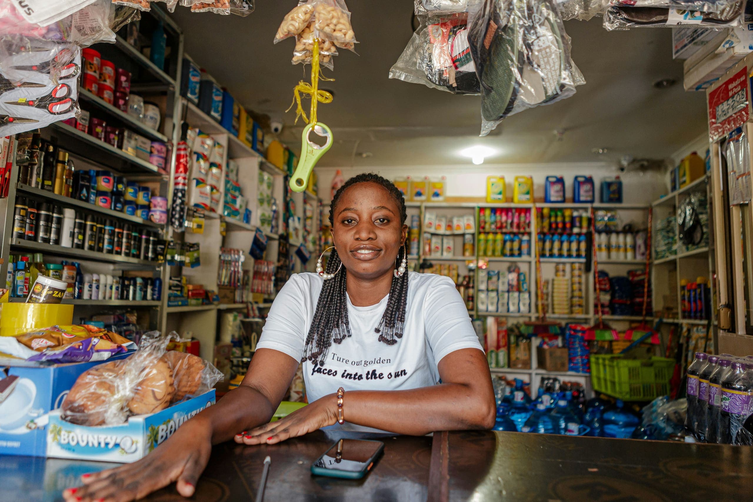 Smiling shop owner leans on the counter of her well-stocked general store
