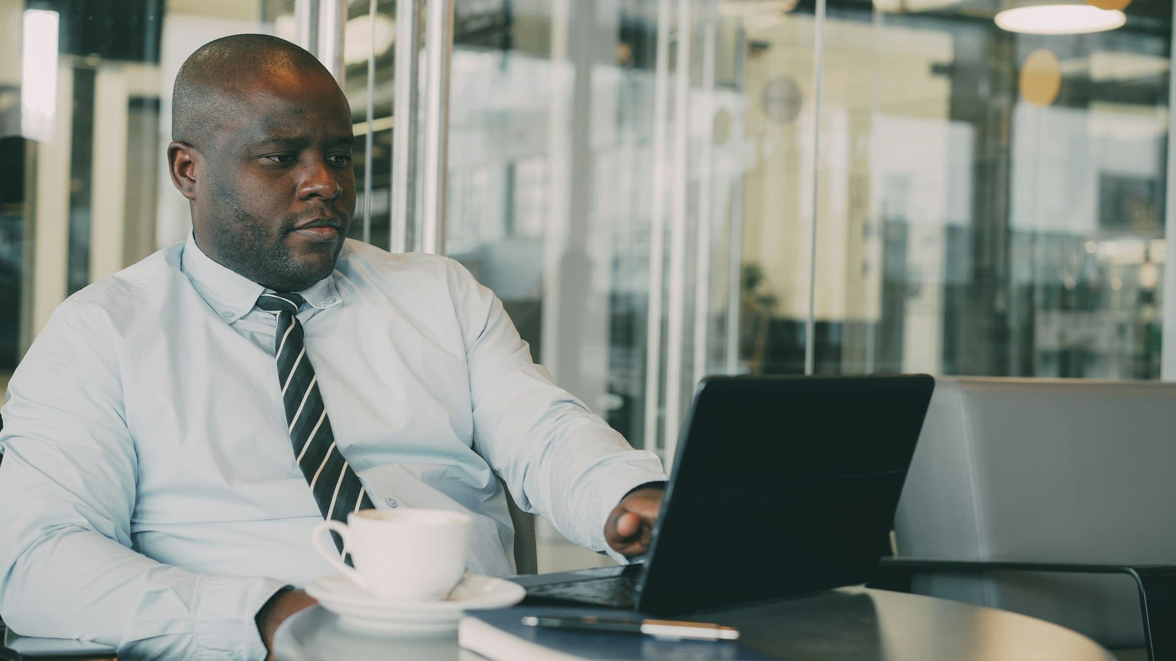 Businessman in shirt and tie works on a laptop in a bright modern office