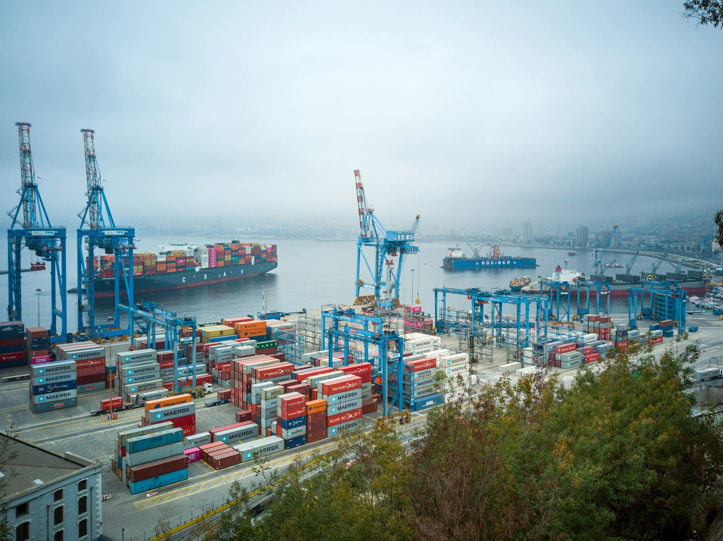 Busy container port with gantry cranes, stacked shipping containers and a cargo ship